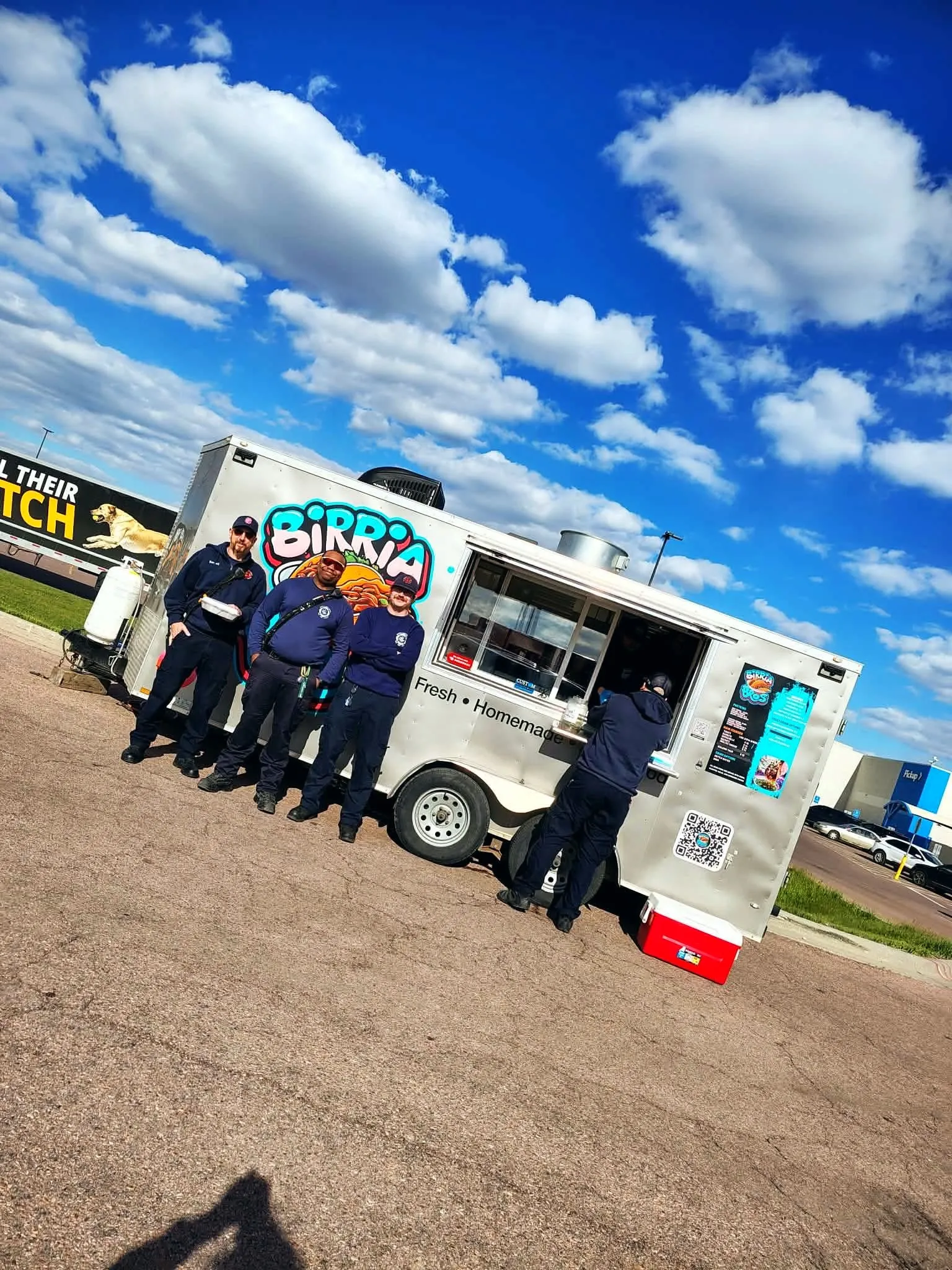 Four first responders posing in front of the Birria Bros truck