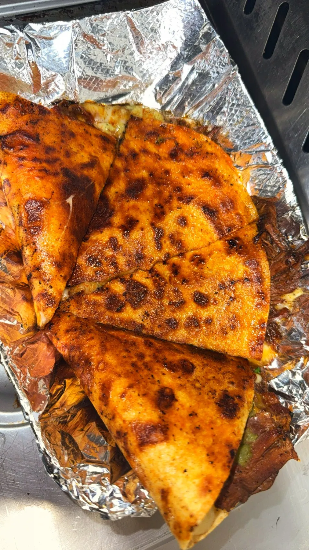 Griddle-charred birria quesadilla wedges in foil